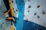 A woman doing rock climbing a style called 'bouldering' indoors