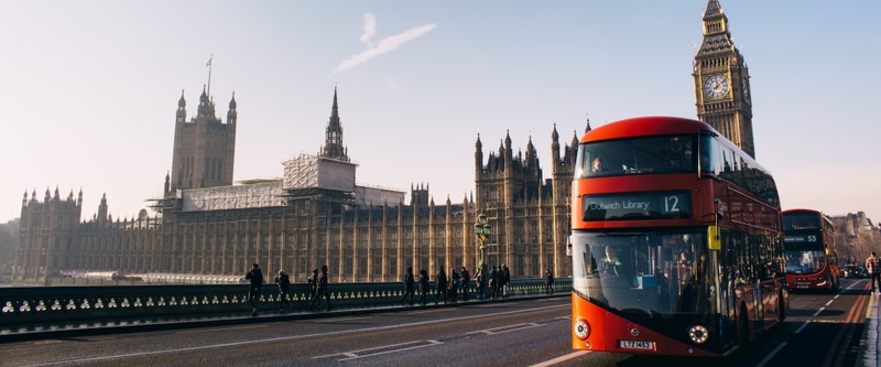 Red double-decker bus passing Palace of Westminster, London