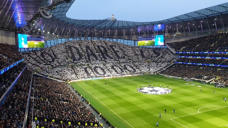 The South Stand of Tottenham Hotspur Stadium, also known as the Park Lane end, before the UEFA Champions League quarter-final with Manchester City F.C. on 9 April 2019, with fans displaying the club motto 'To Dare Is to Do'. (© Bluejam, CC BY-SA 4.0)